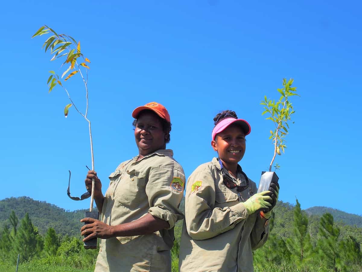Two women holding trees for a mahogany glider tree planting in the wet tropics